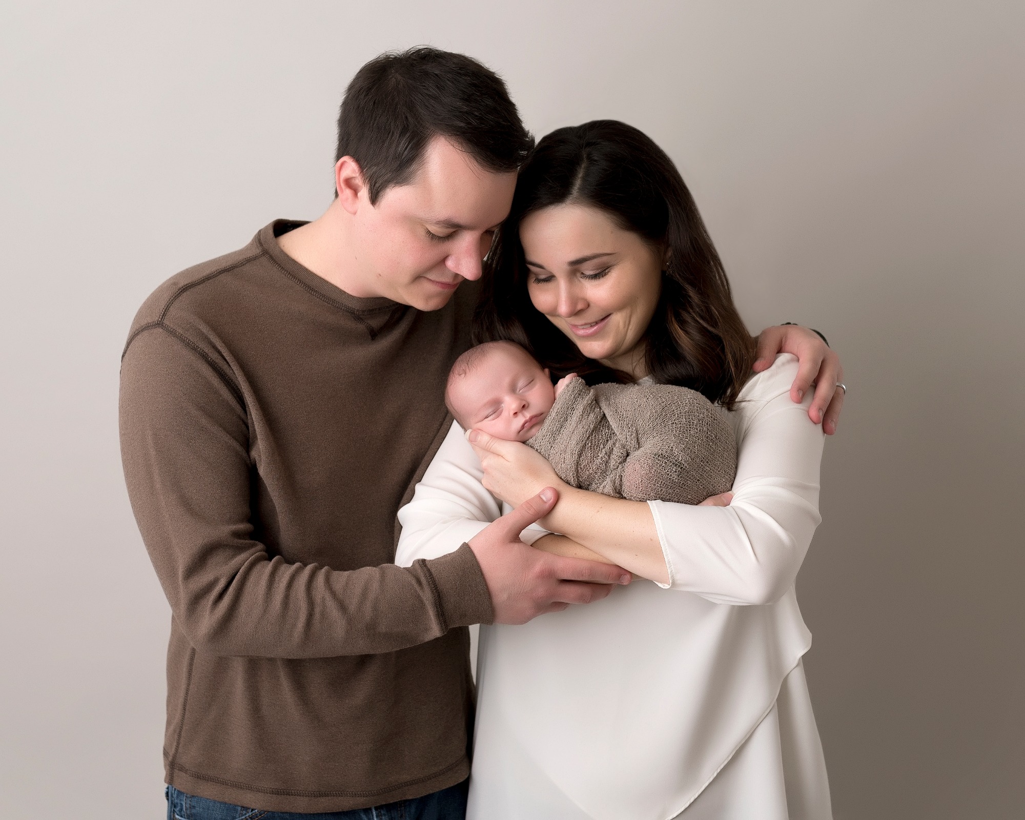 mom and dad holding newborn baby in neutral colors Houston Birthing Centers