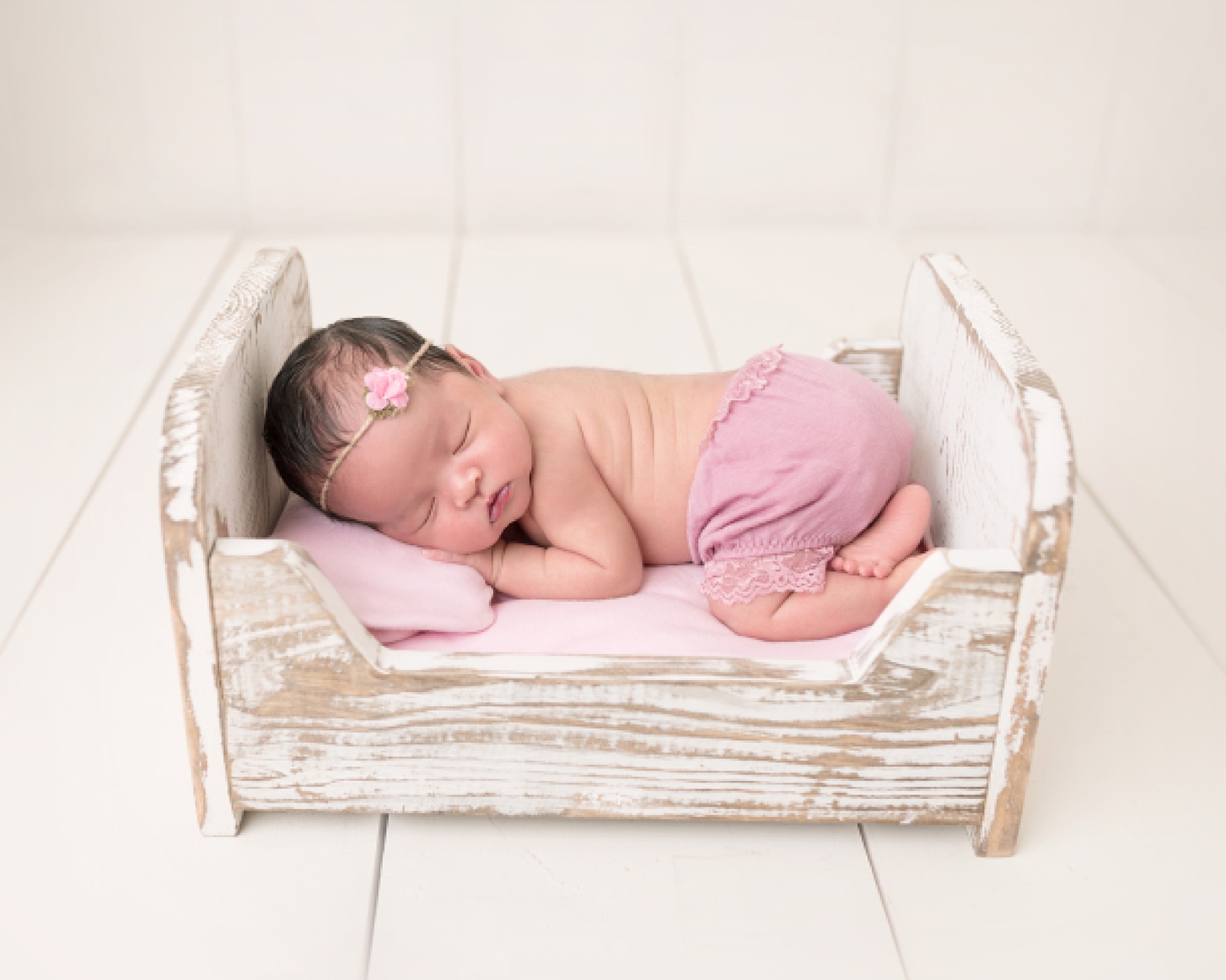 newborn baby girl sleeping on a bed in a pink wrap Houston Lactation Consultants
