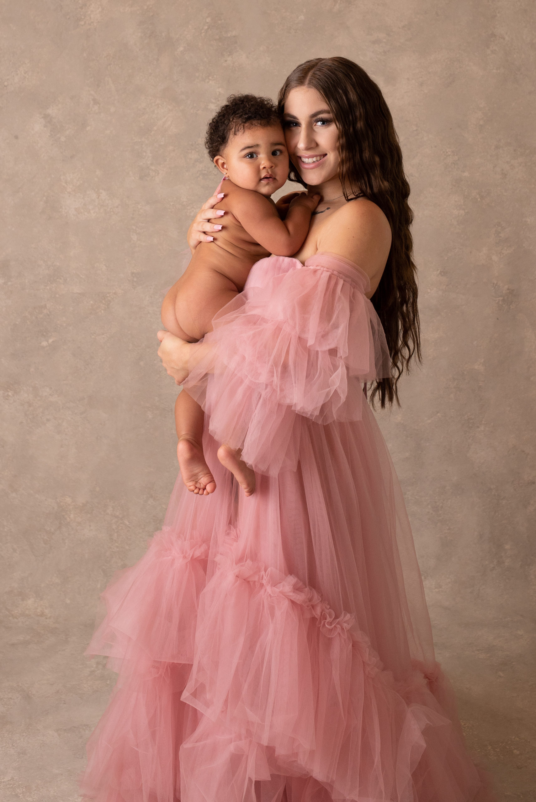 mom holding newborn in pink gown