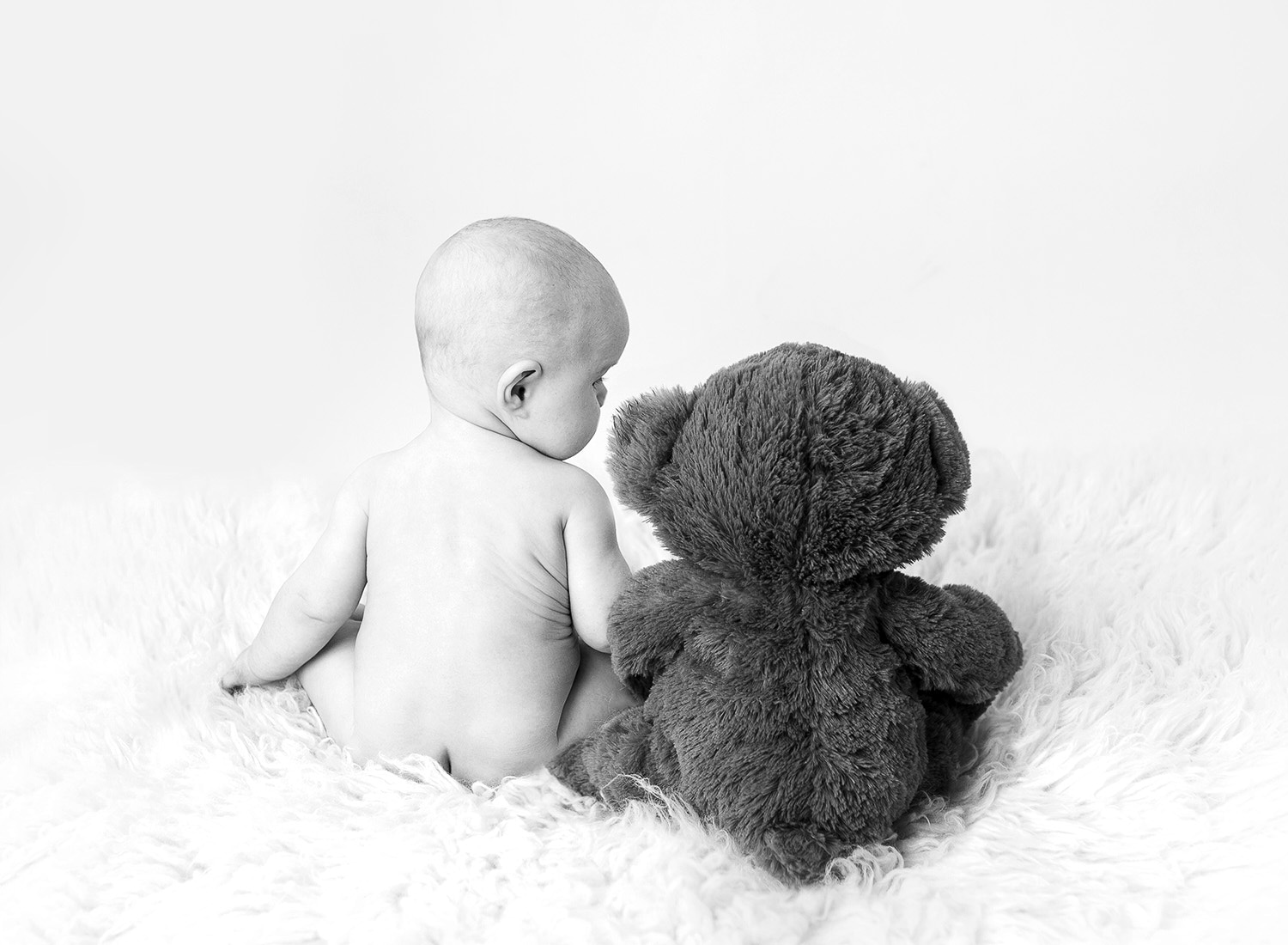 Baby looking at a stuffed teddy bear