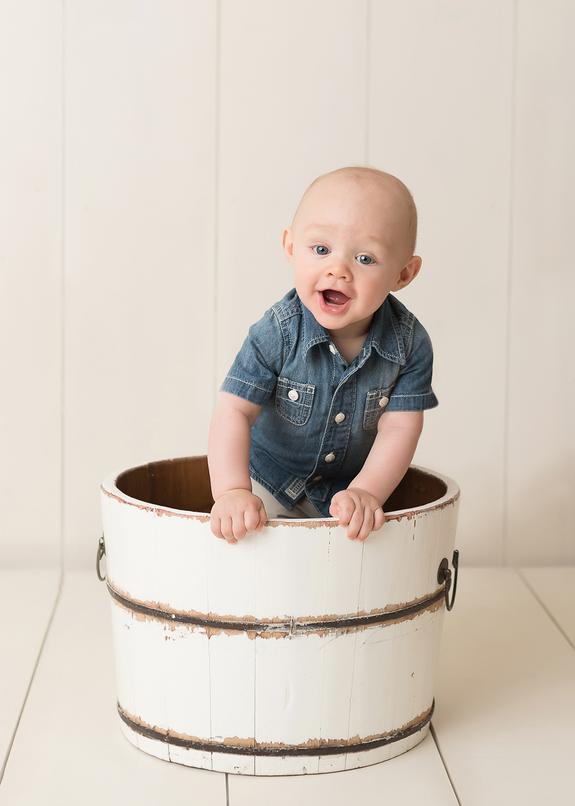 little boy in denim shirt playing in a bucket baby clothes houston