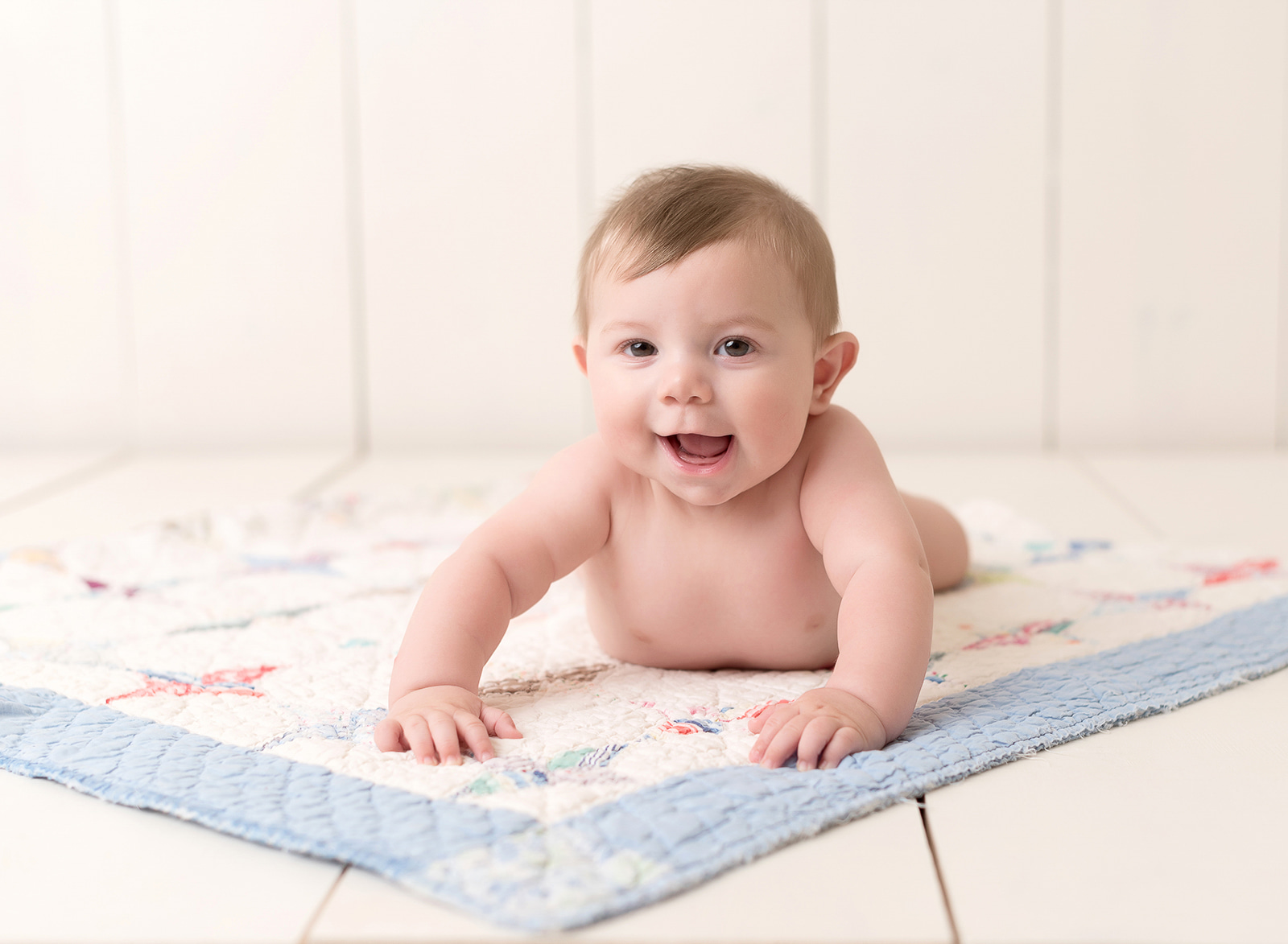 baby laying and smiling on a blanket Houston Nanny Agency