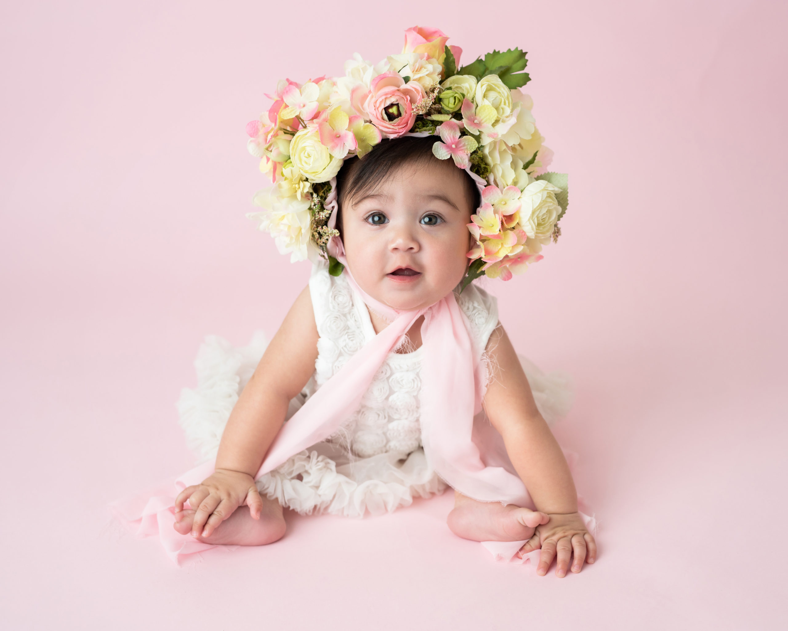 little girl with a flower hat on a pink backdrop