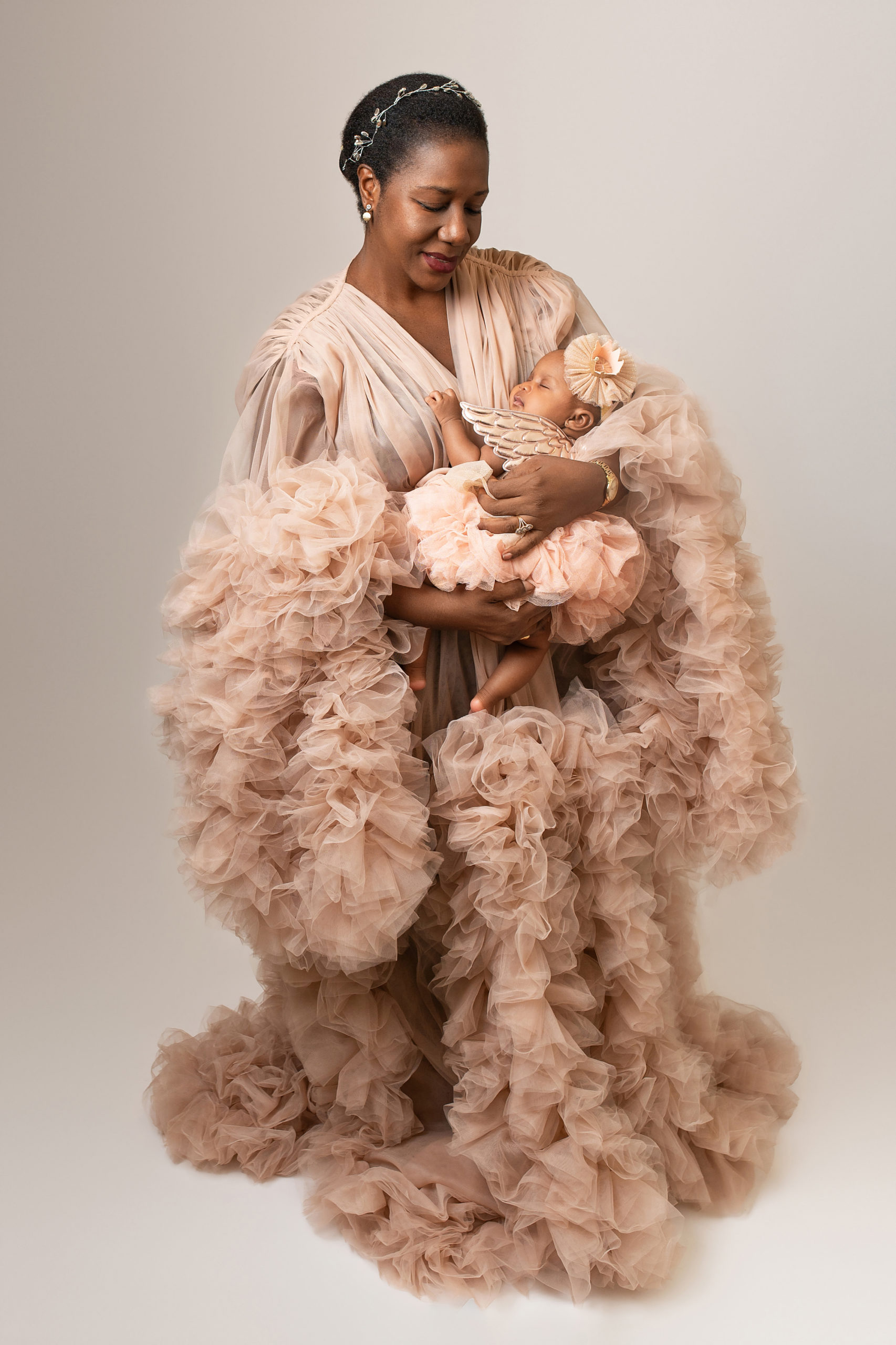 new mom in tan tulle maternity robe holding her newborn
