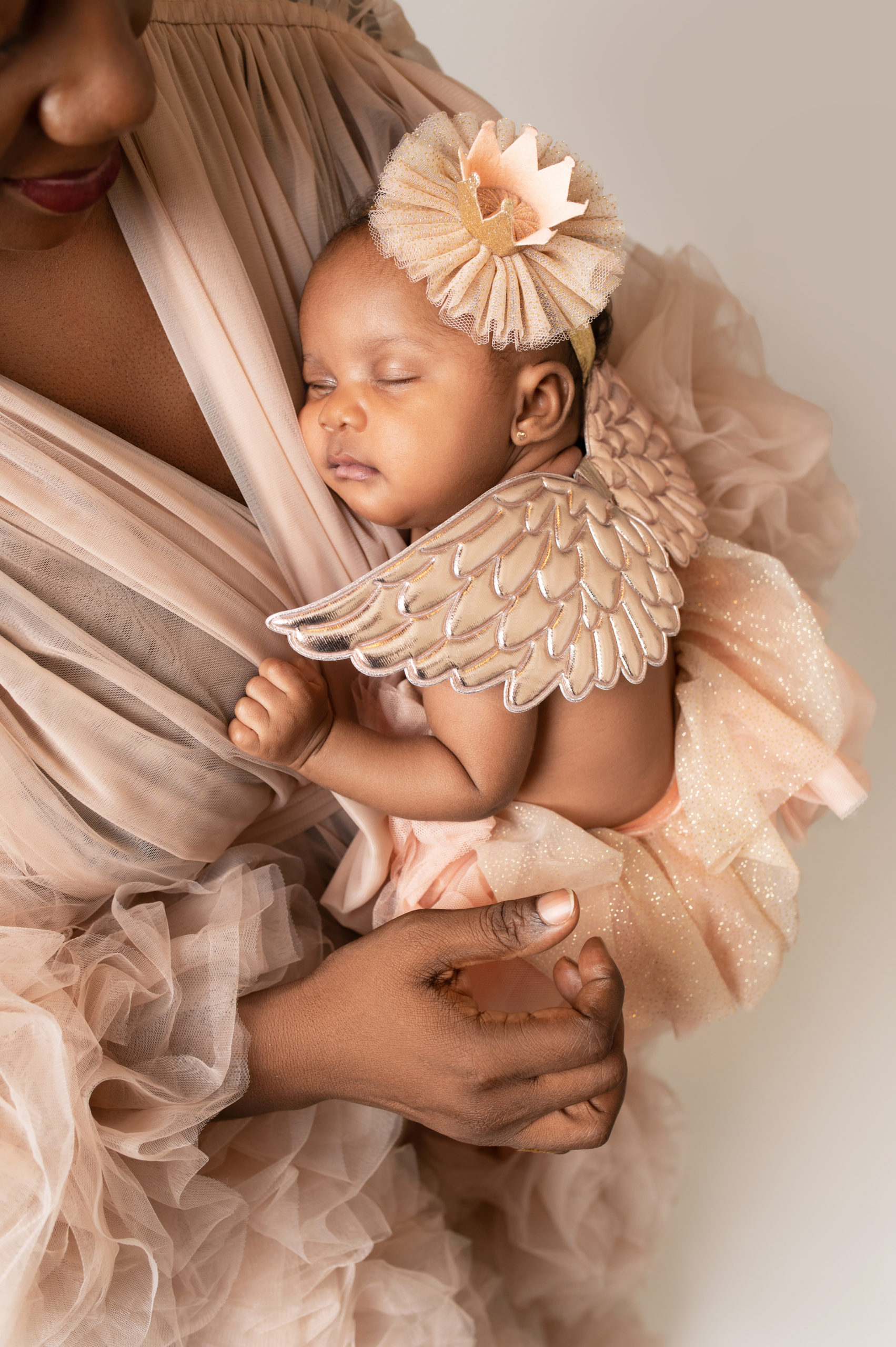 newborn girl in tulle tan dress and wings snuggling on her mom Kandiland league city