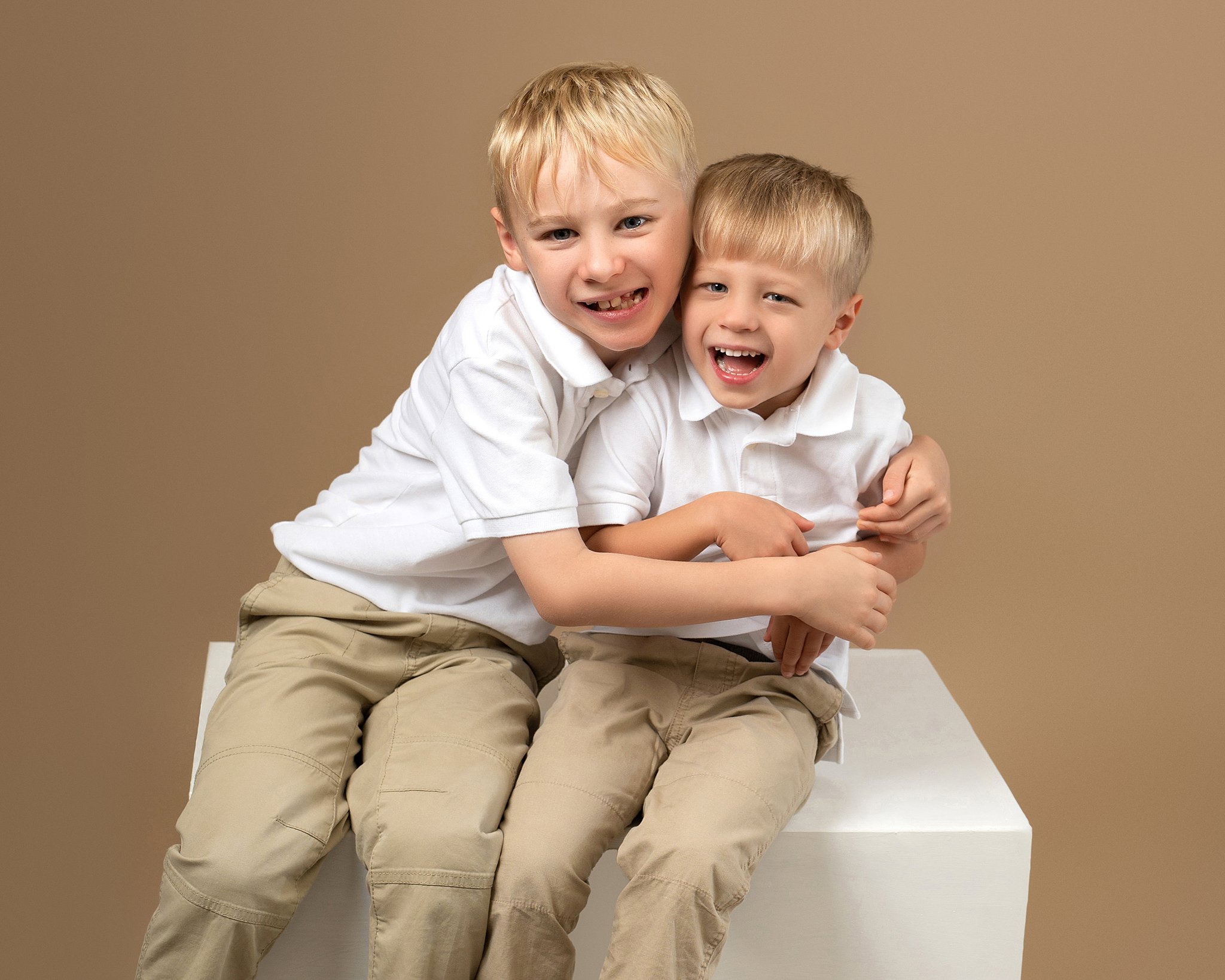 Two boys sit on a white cube in a studio Kids atelier