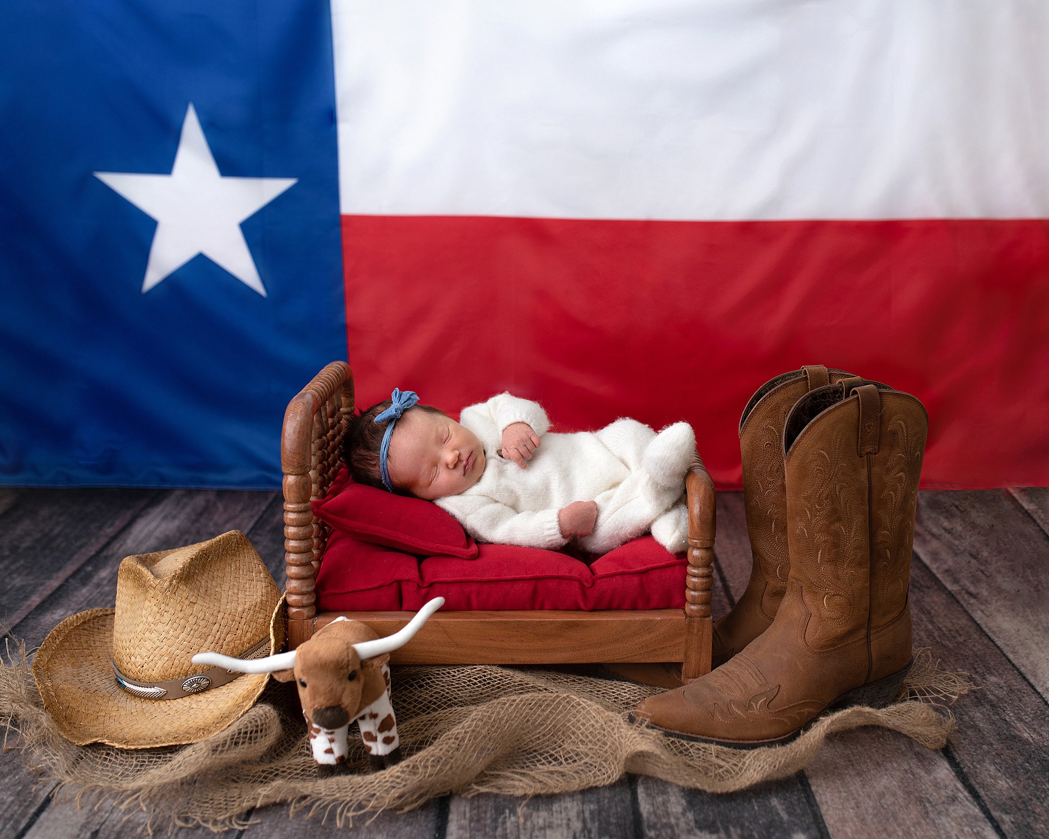 newborn sleeps on a wooden ben with texas flag backdrop and cowboy boots houston methodist childbirth center
