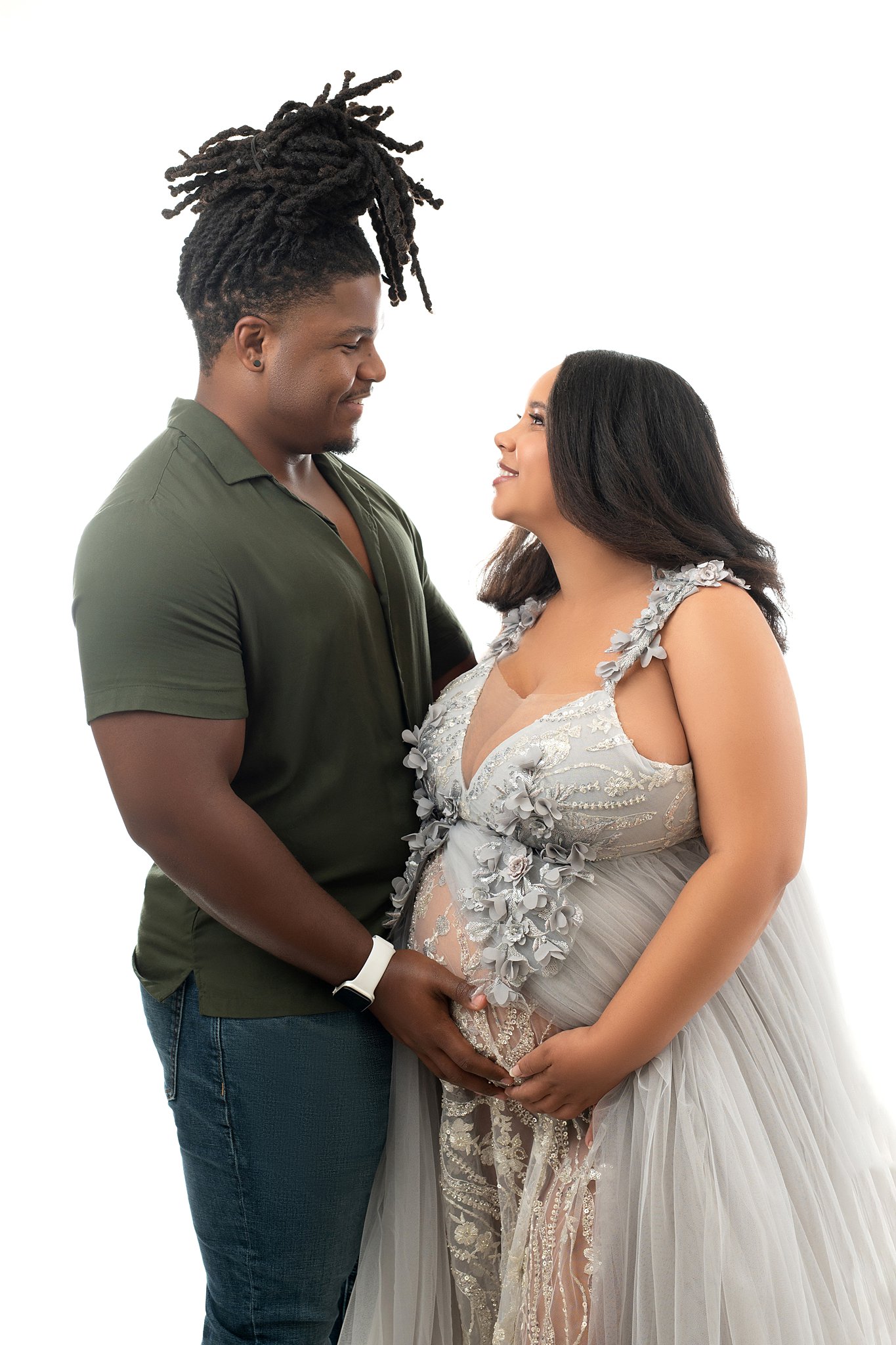 parents-to-be stand in a studio holding the bump