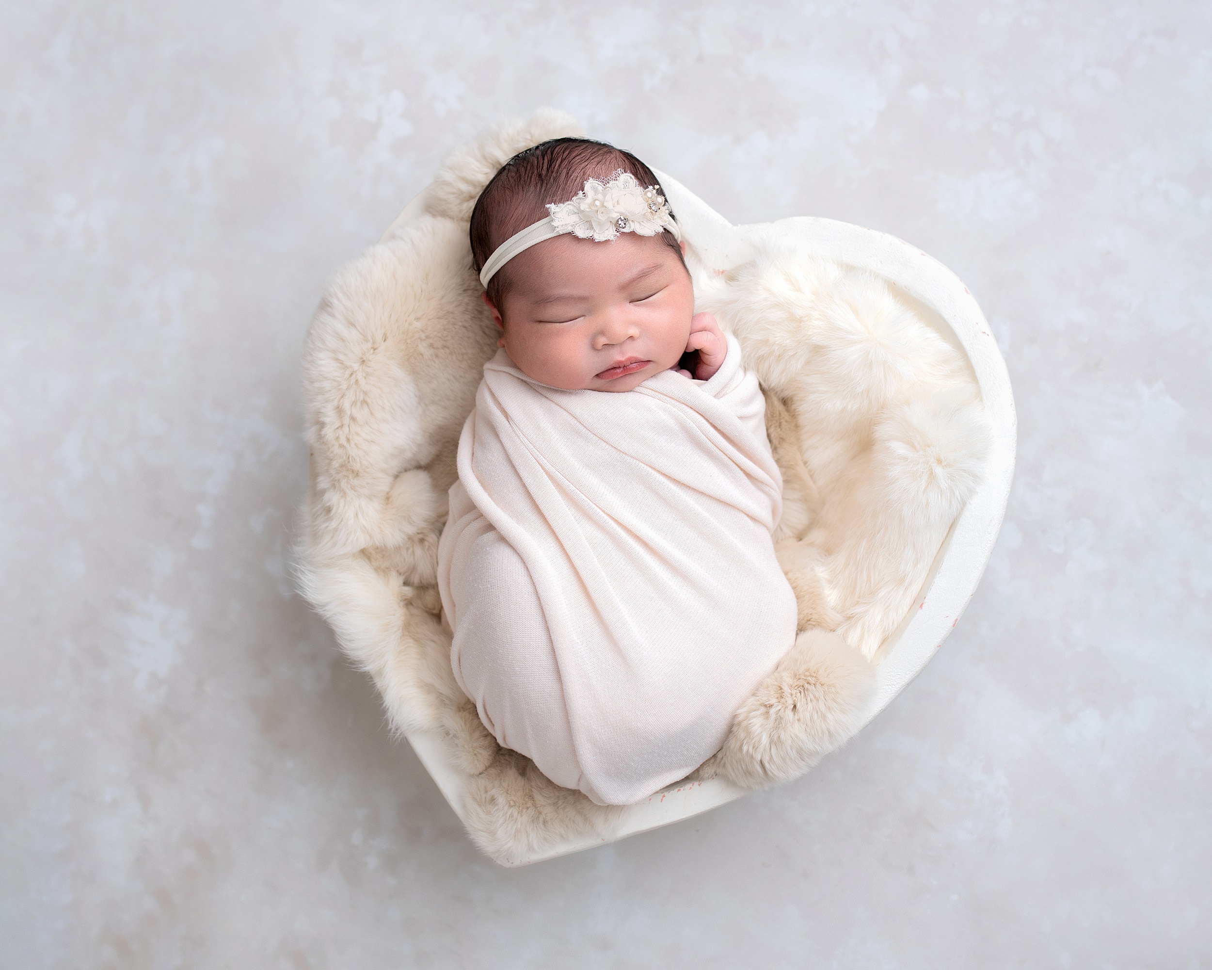 newborn baby girl sleeps in a heart-shaped bed Itsy Bitsy Boutique Houston