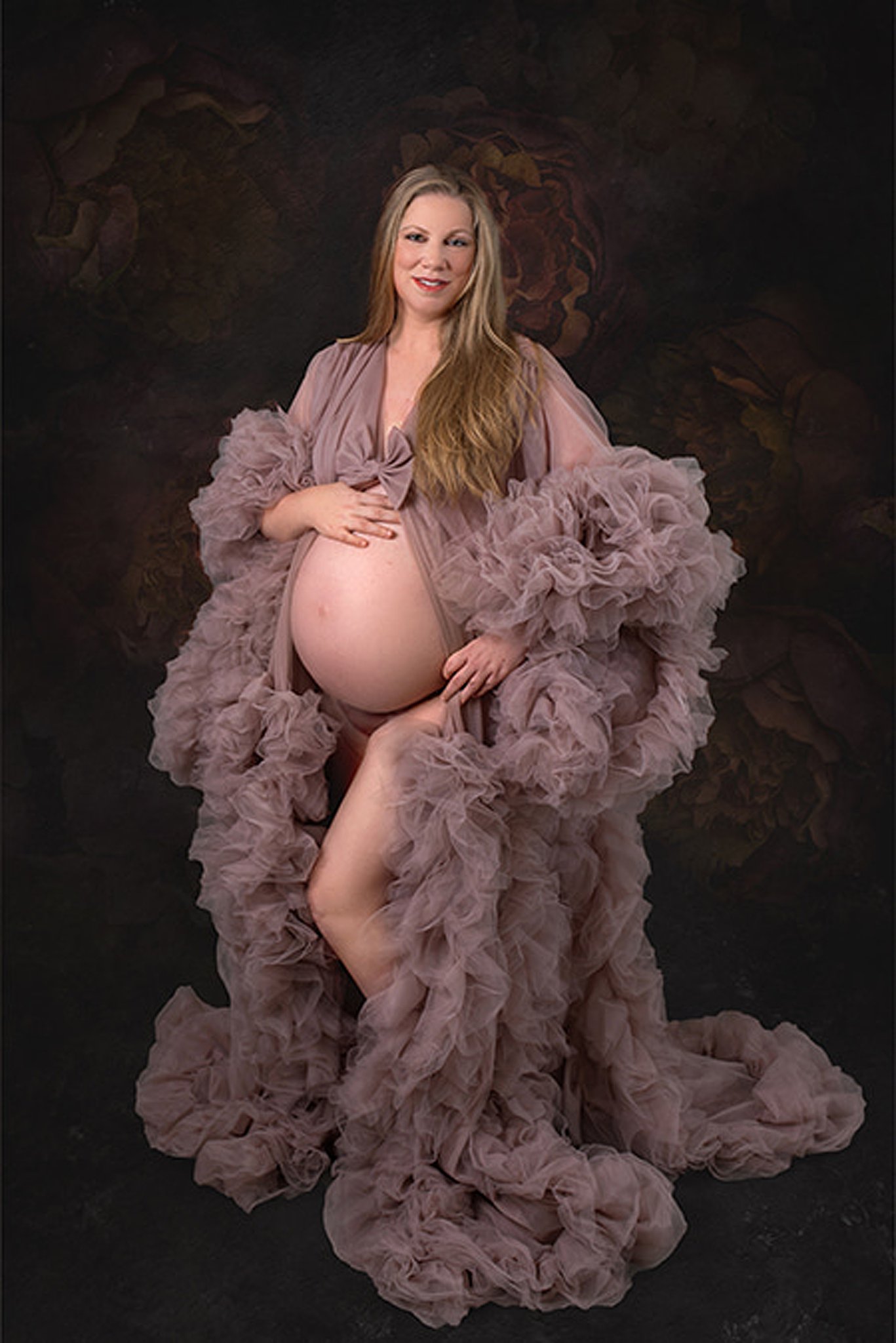 A large tule dress envelopes a mother to be standing with bump exposed in a studio Texas Childrens Pavilion