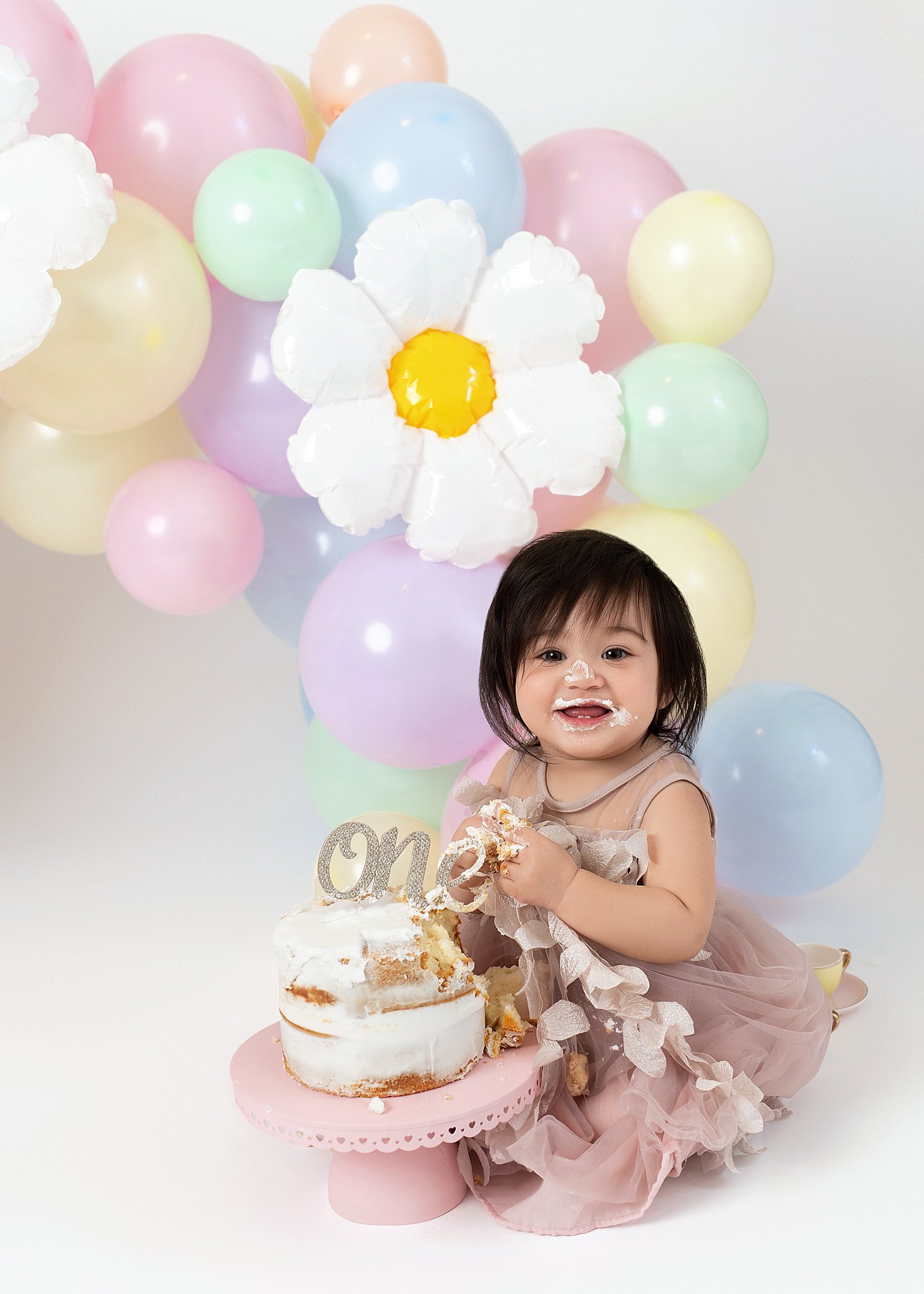 One year old girl sits in a studio smashing a birthday cake The Children’s Place in Houston