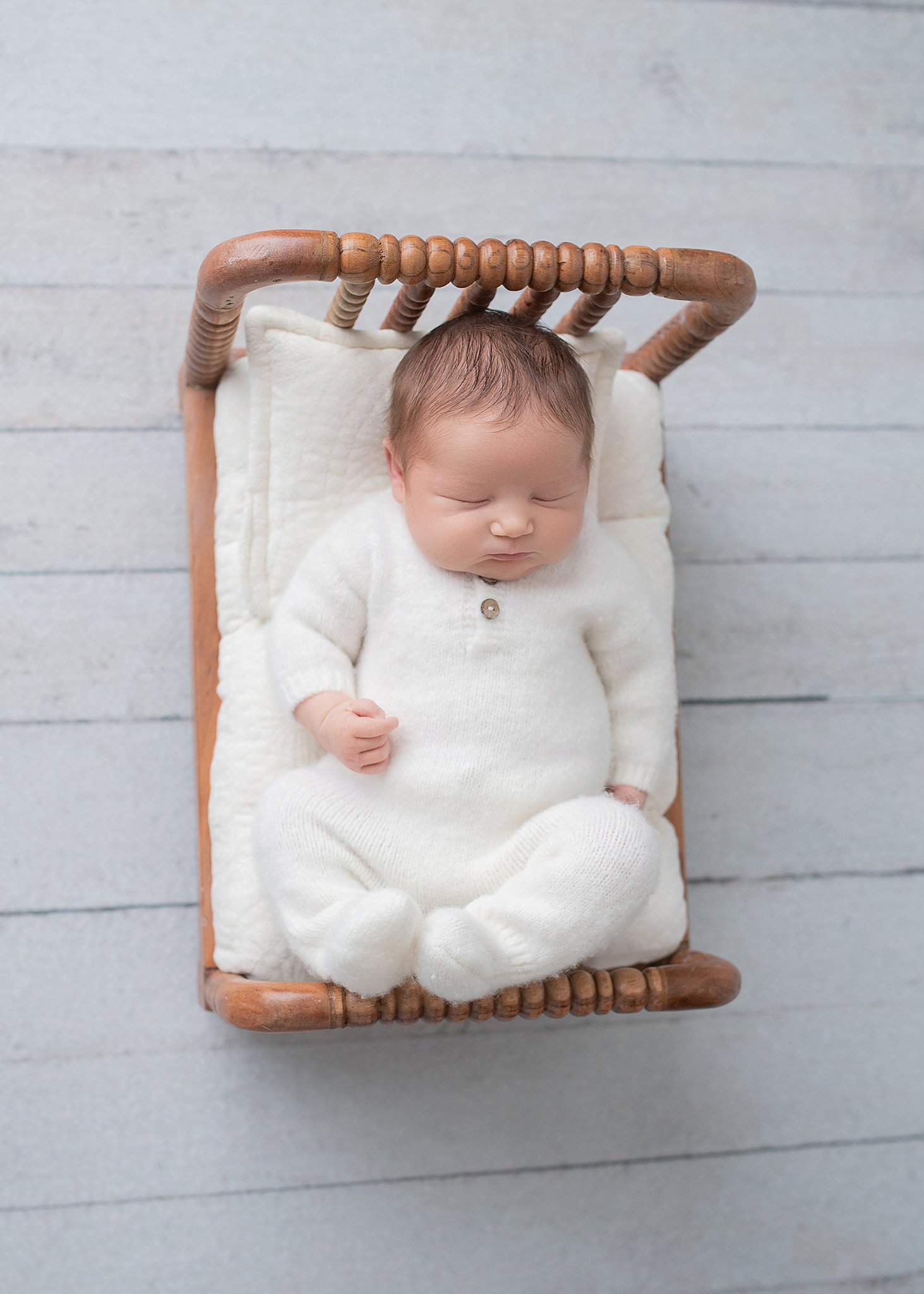 newborn baby sleeps in a wooden bed wearing a white onesie baby furniture stores in Houston