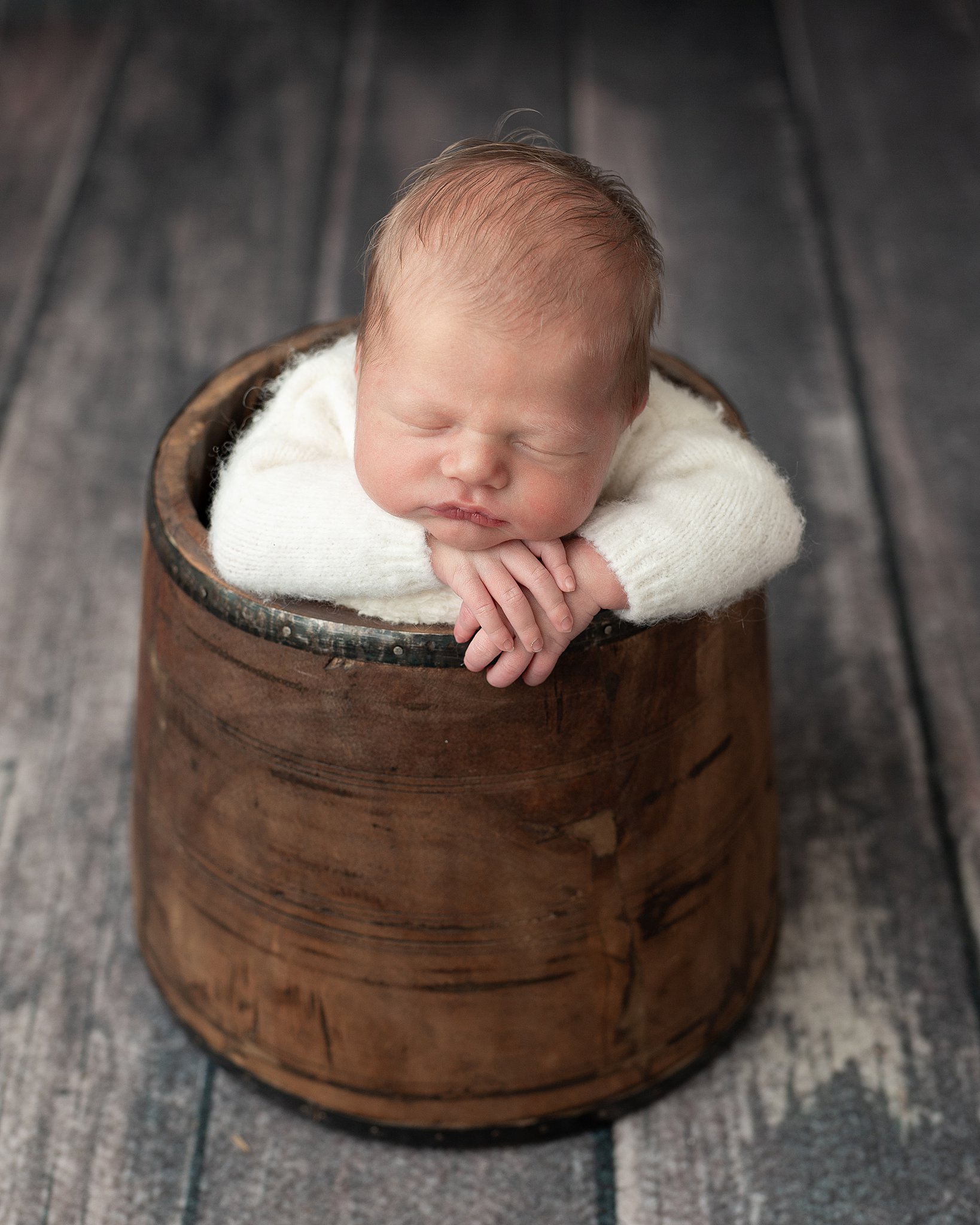 a newborn baby sleeps on it's hands inside a wooden bucket homebirth experience